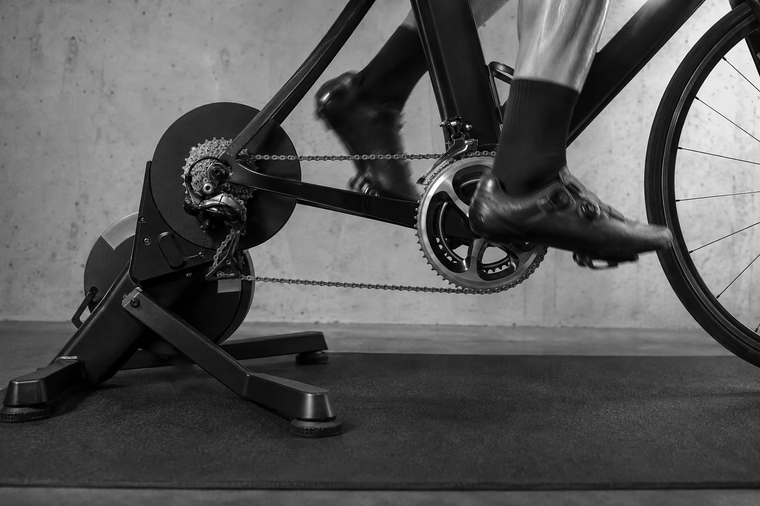 A cyclist pedaling a road bike on an indoor smart trainer.